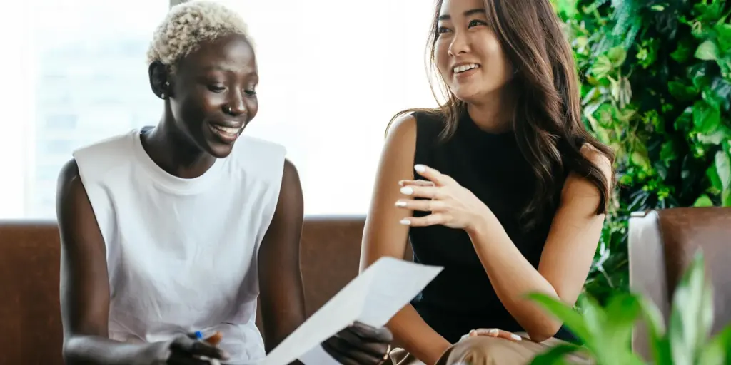 Two people of different backgrounds cheerfully discussing a paper